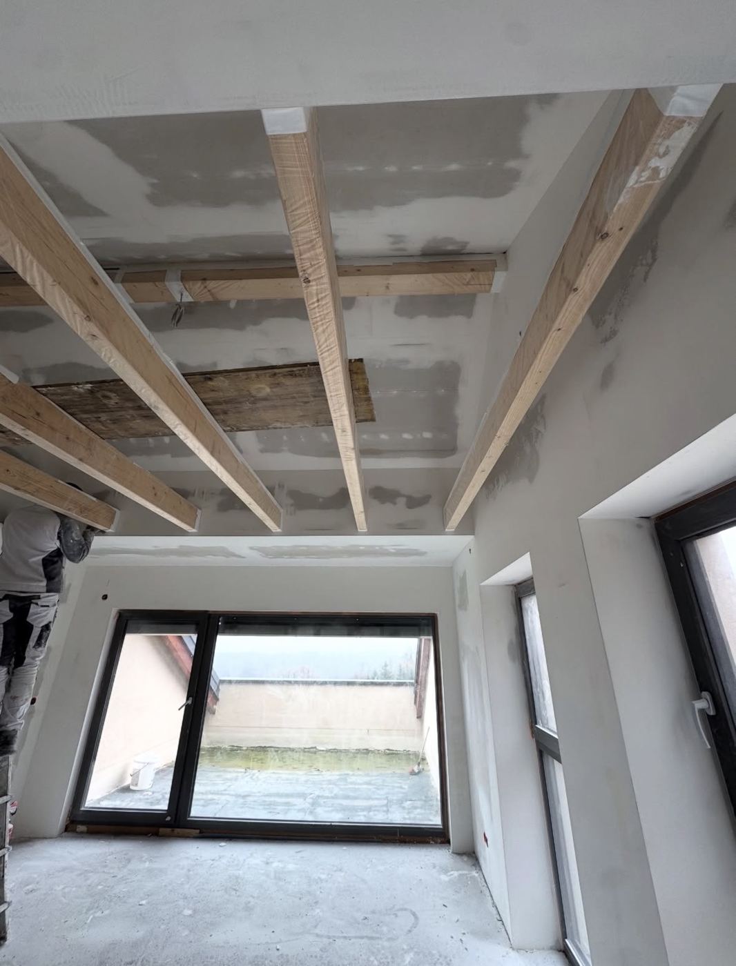 Dachgeschoss mit Holzbalken: Decke und Wände gegipst, sichtbare Balken sauber eingebunden.